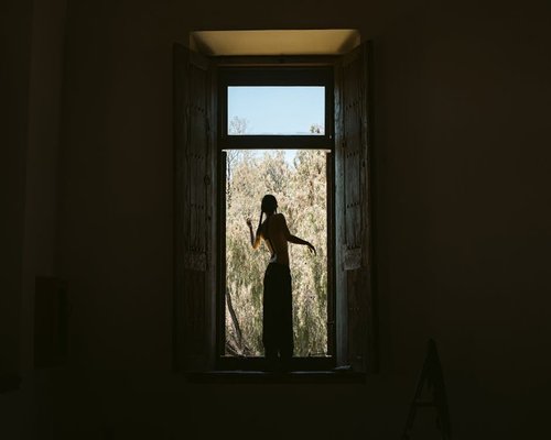 Persona estirándose suavemente junto a una ventana